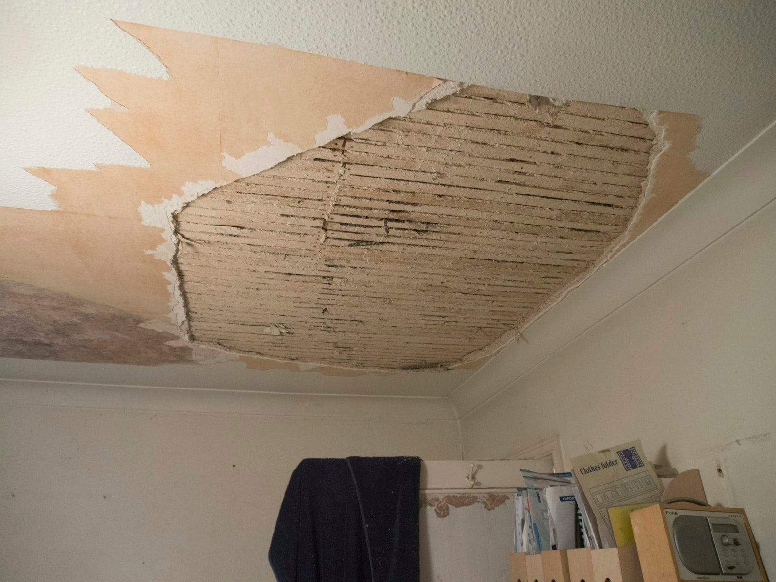 Room with water-damaged ceiling drywall torn away