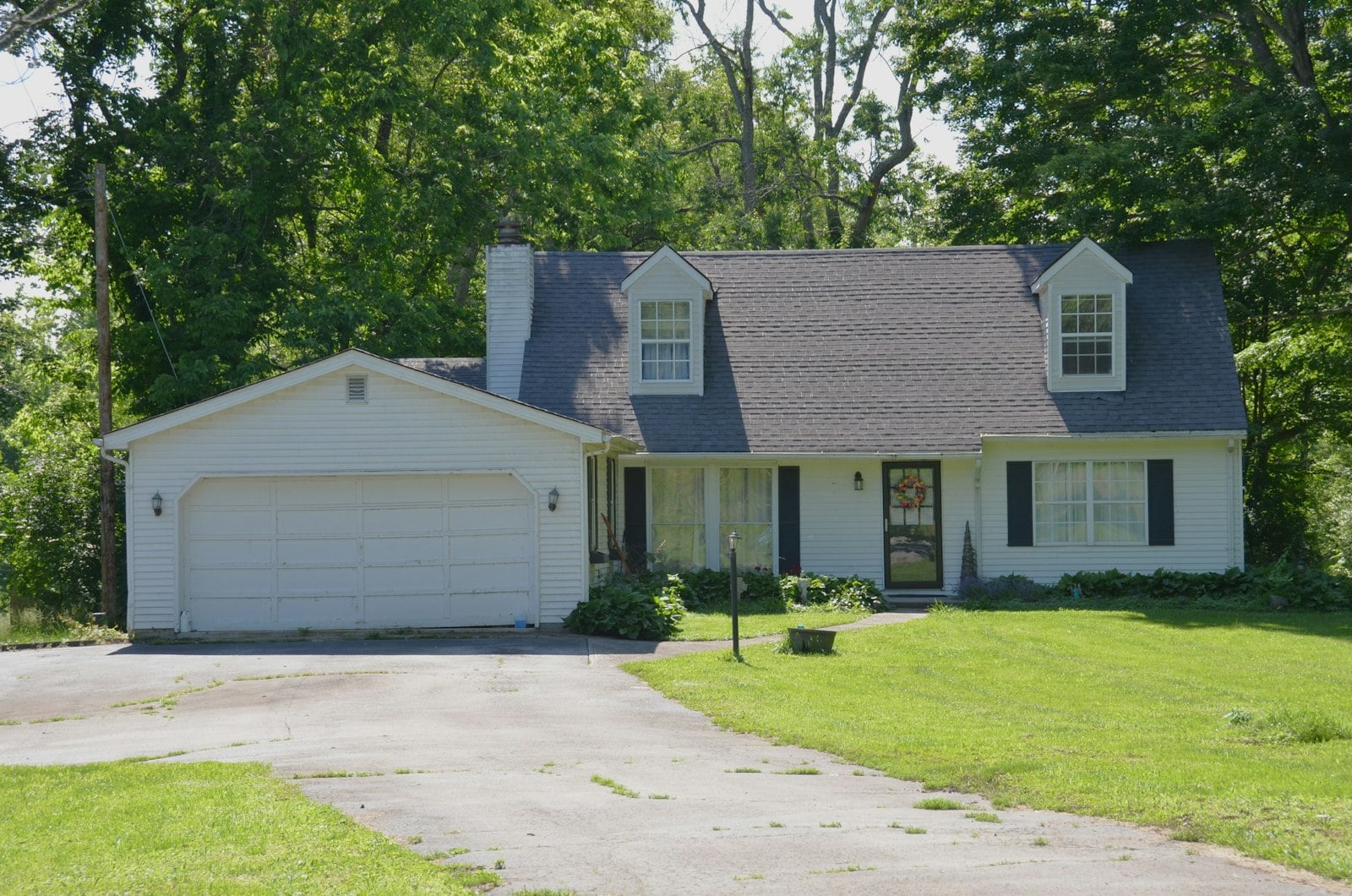 White house with a garage, driveway and green lawn